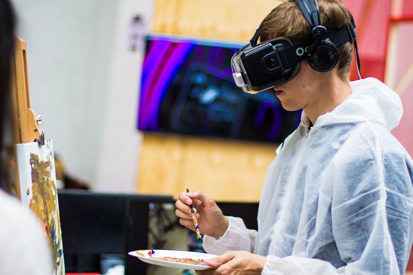 Picture of a boy painting on a canvas with VR-goggles